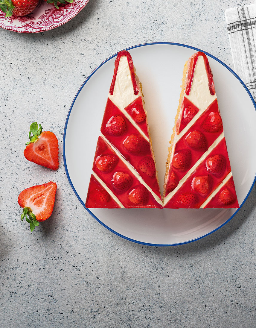 Zwei Stücke Erdbeerkuchen in Zuckerhutform liegen auf einem Teller.