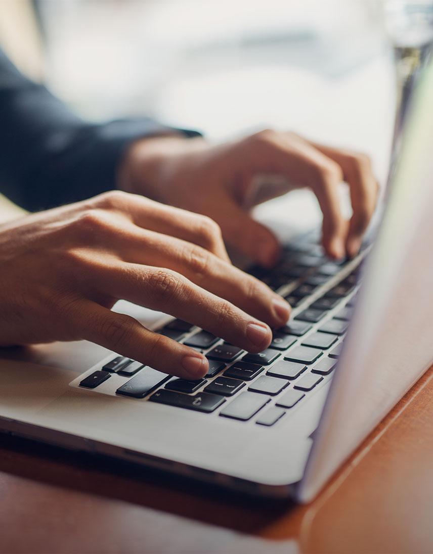 Hände tippen auf einer Laptop-Tastatur.