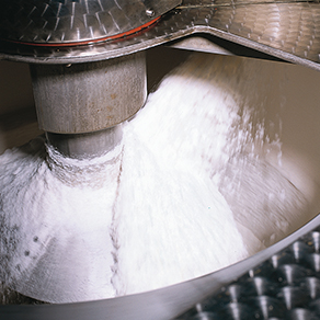 Weißer Zucker in einer industriellen Produktionsanlage während der Verarbeitung in einem Metallbehälter.